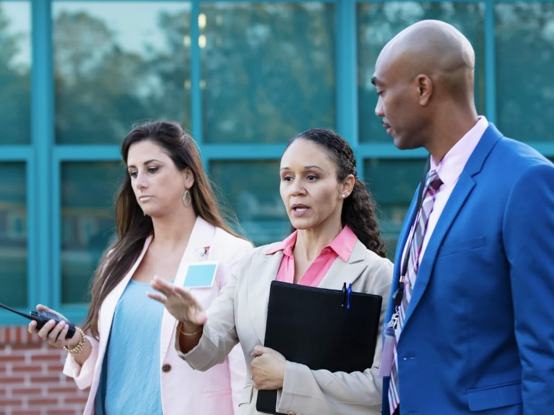 Administrators talking in front of school